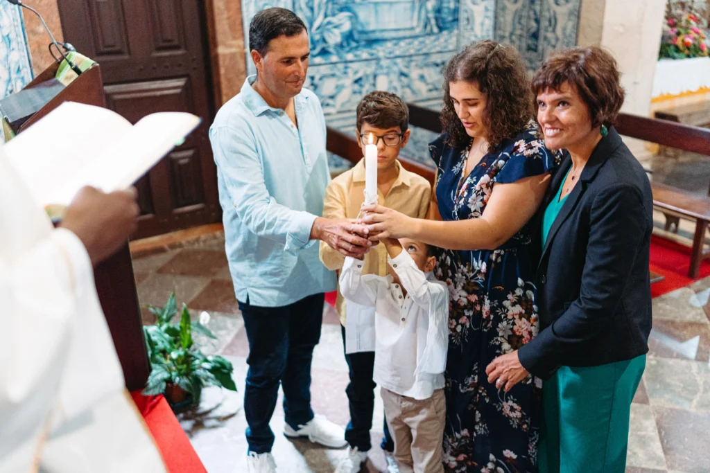 A family holds a lit candle together during a baptism ceremony in Portugal.