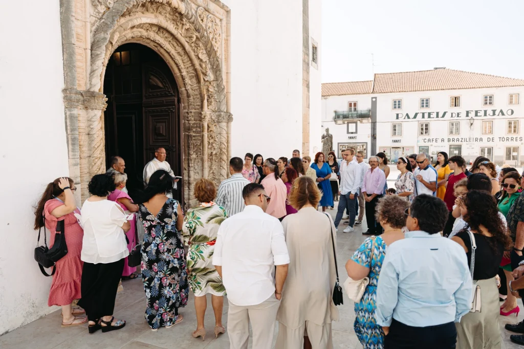 A group of family and friends gather outside a historic church in Portugal for a baptism ceremony.