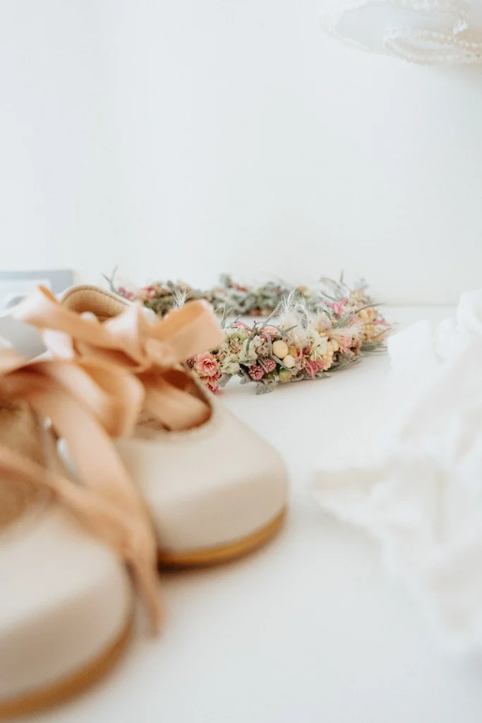 Soft-focus details of baby shoes and a floral crown, capturing the essence of a baptism celebration in Portugal.