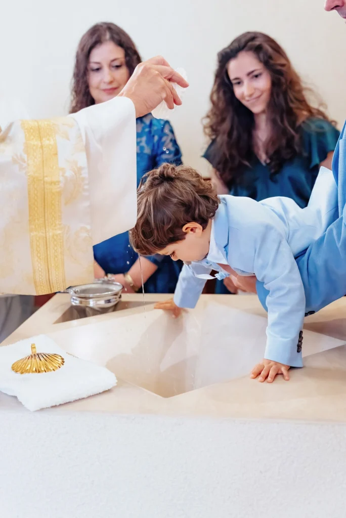 A priest pouring holy water over a toddler’s head during a baptism ceremony in lisbon