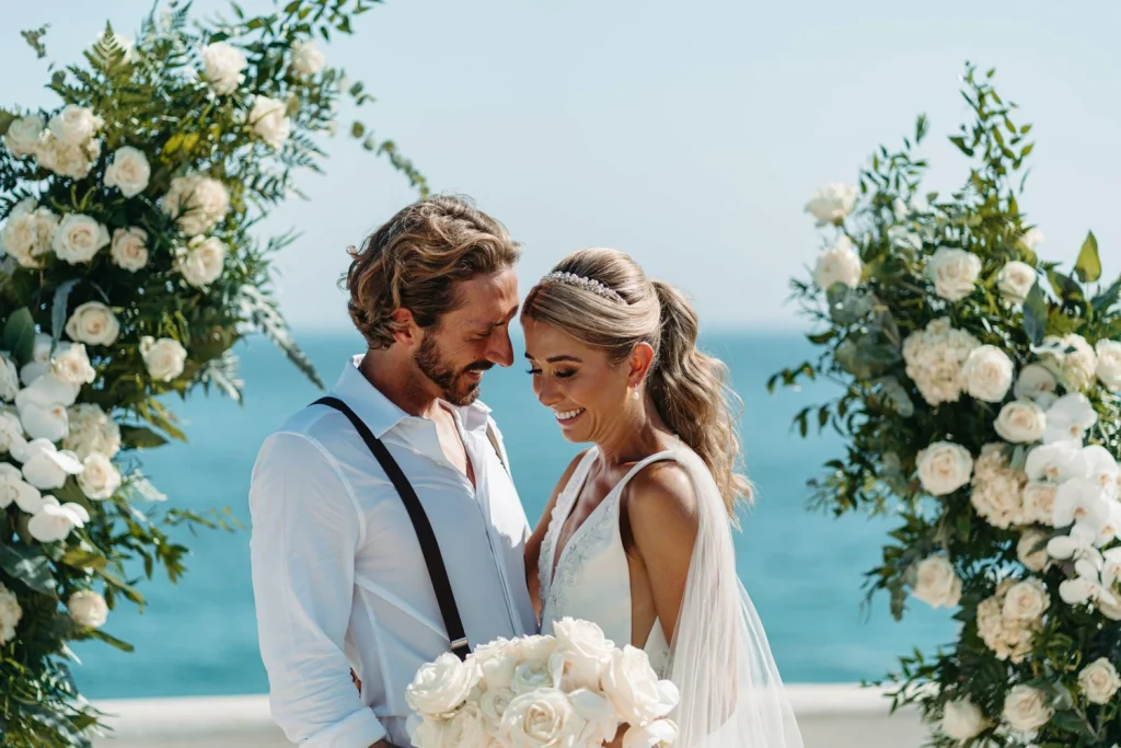 Newlywed couple walking joyfully with their wedding party, holding champagne glasses and celebrating their marriage.
