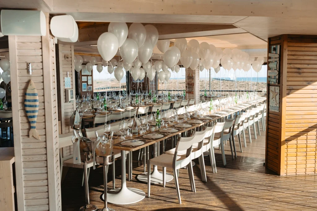 A perfectly arranged dining table with white balloons and ocean views, set for an elegant beachside event in lisbon