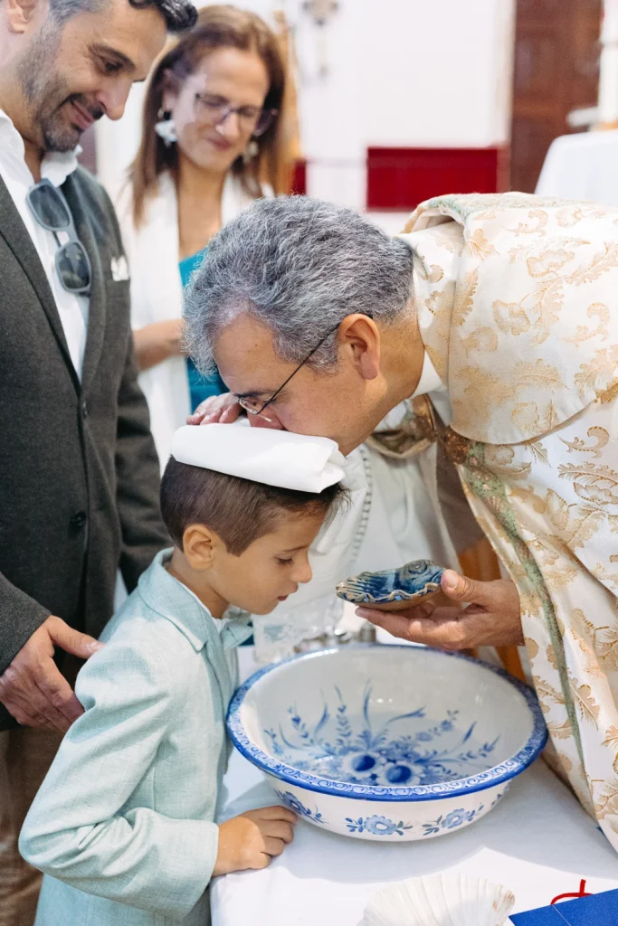 Priest blessing a young boy during a baptism ceremony in a church in Portugal