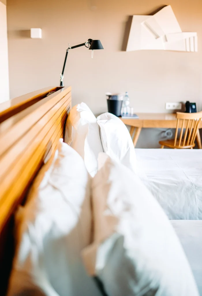 A beautifully designed boutique hotel room with crisp white bedding and stylish wooden details.