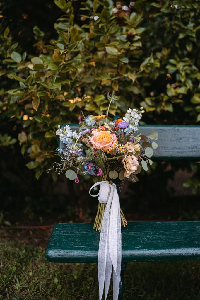A vibrant bridal bouquet with fresh flowers resting on a rustic green bench