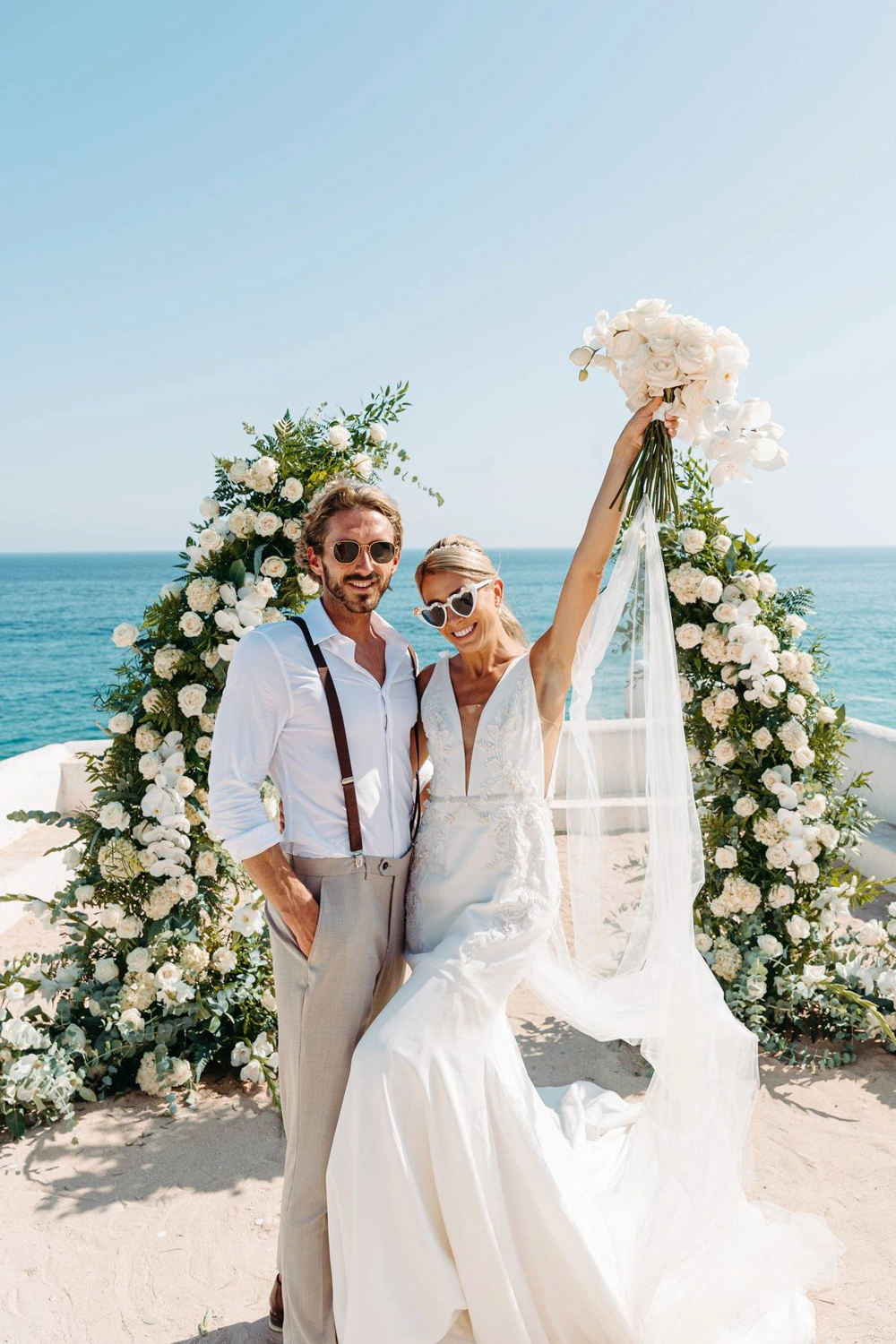 Newlywed couple walking joyfully with their wedding party, holding champagne glasses and celebrating their marriage in Algarve