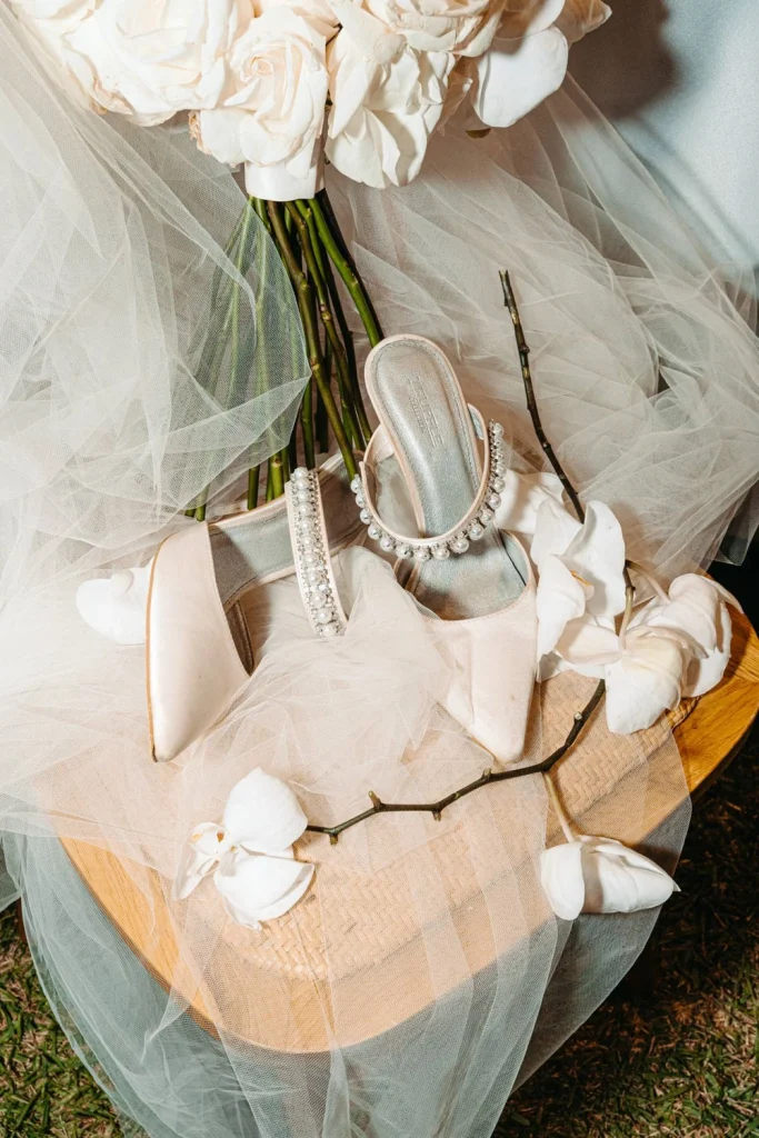 Bridal bouquet, wedding shoes, and elegant veil styled beautifully on a vintage chair.