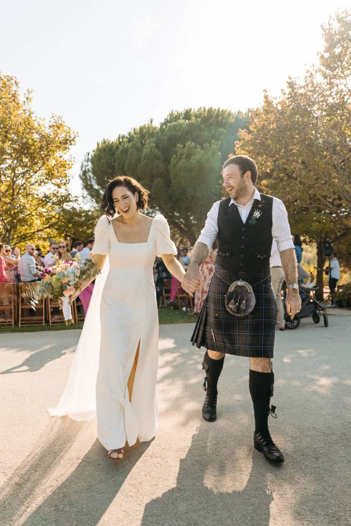 The bride and groom walking hand in hand along a scenic garden path, bathed in golden hour light.