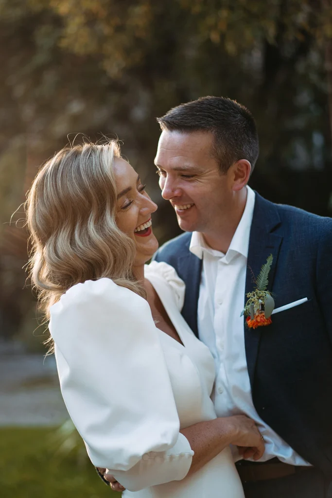 A joyful moment as the bride and groom share laughter in an intimate wedding portrait.