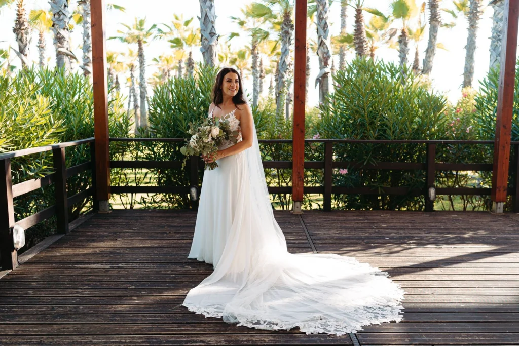 A beautiful bride, smiles while posing with her wedding bouquet in a tropical setting. Filename: anita-aidan-wedding-reception-decor