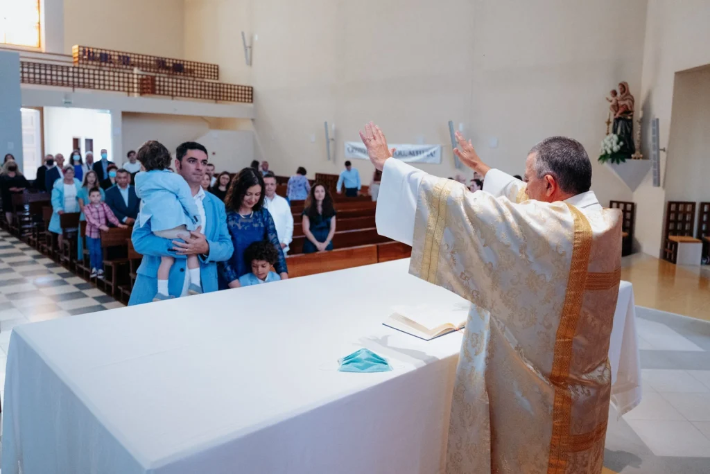 A priest blessing a family during a baptism ceremony inside a church.