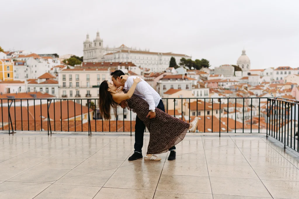 A couple stands close on a Lisbon rooftop, soaking in the breathtaking views and golden-hour glow.
