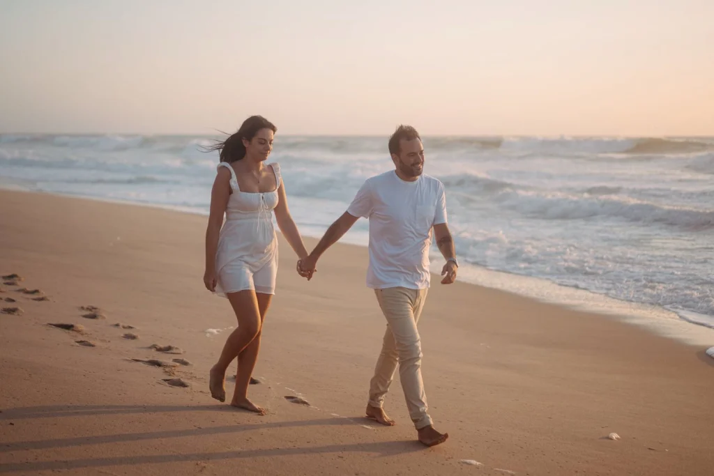 Couple embracing on a cliffside overlooking the ocean during a sunset engagement session in Portugal.