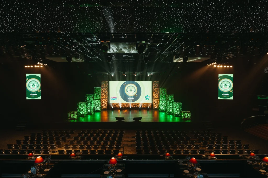 An elegant stage setup at a corporate awards gala, featuring green and gold lights with a professional ambiance in estoril