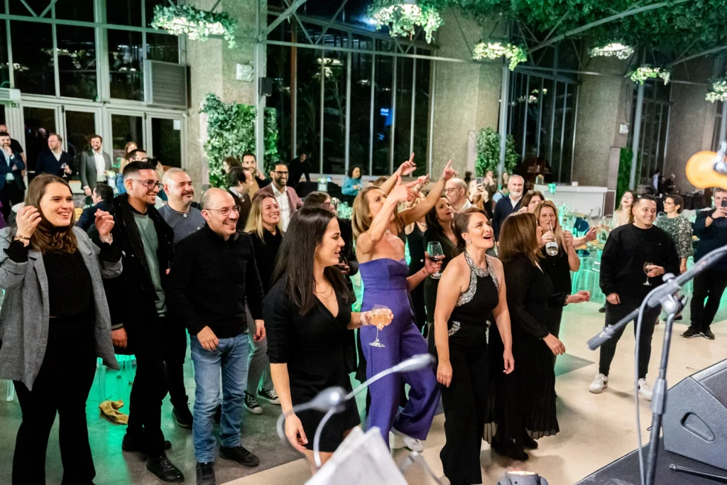 A lively crowd enjoying music and dancing at a corporate event, dressed in elegant evening attire. in estufa fria