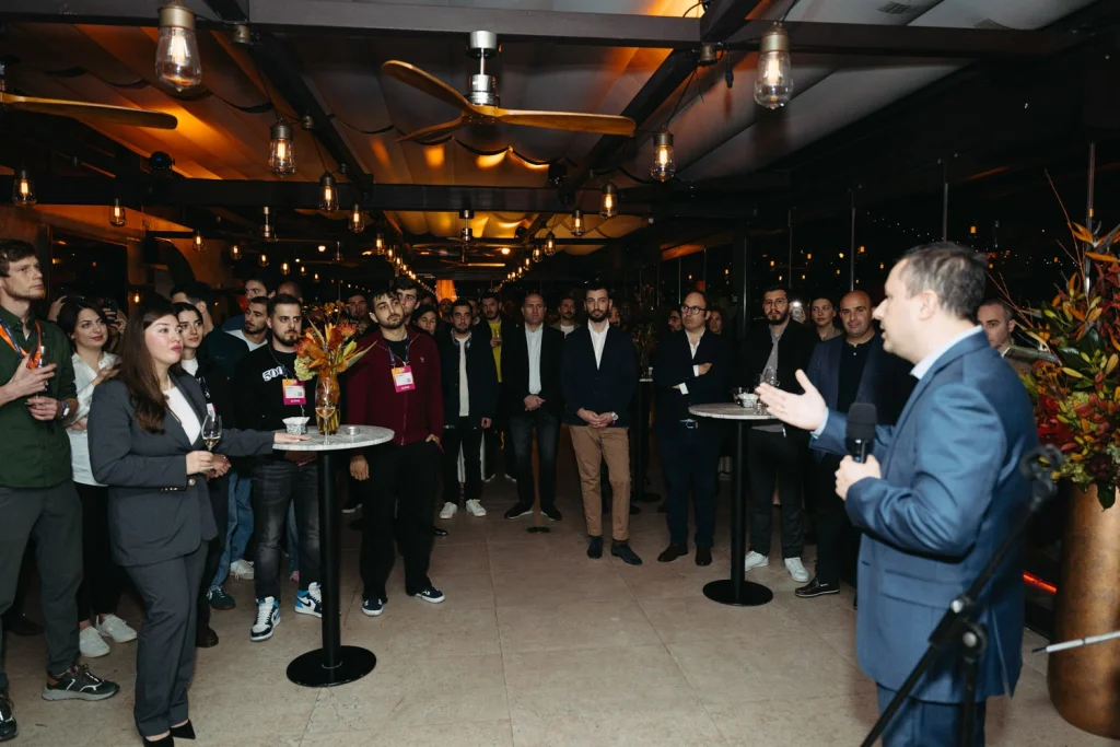 A keynote speaker addressing a room full of professionals at a high-profile business networking event