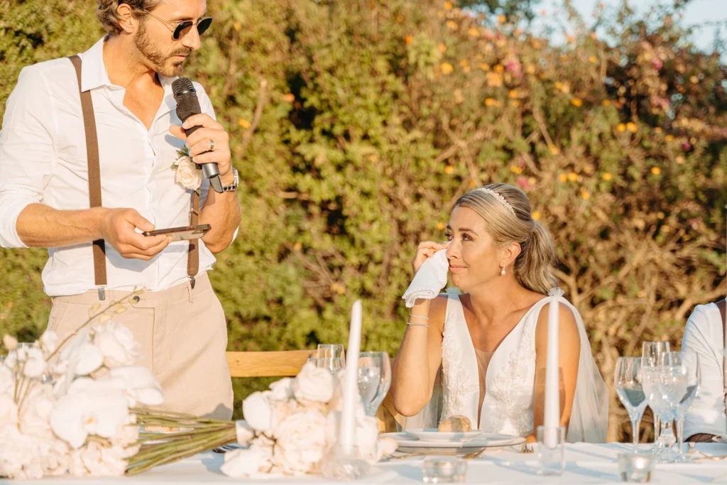 The groom delivers a heartfelt speech at the wedding reception, bringing the bride to tears of joy during their elegant outdoor celebration in Portugal.