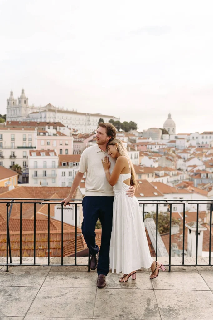 A couple enjoys a quiet moment on a Lisbon rooftop, surrounded by the warm glow of the setting sun.
