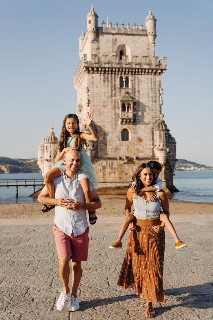 A family of four poses in front of the historic Belém Tower in Lisbon, Portugal, during golden hour.