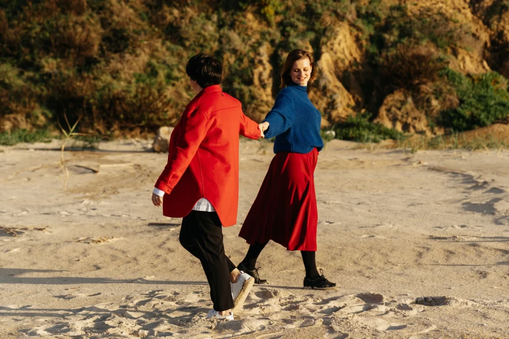Joyful couple laughing and playing in the sand during a Portugal beach photoshoot.