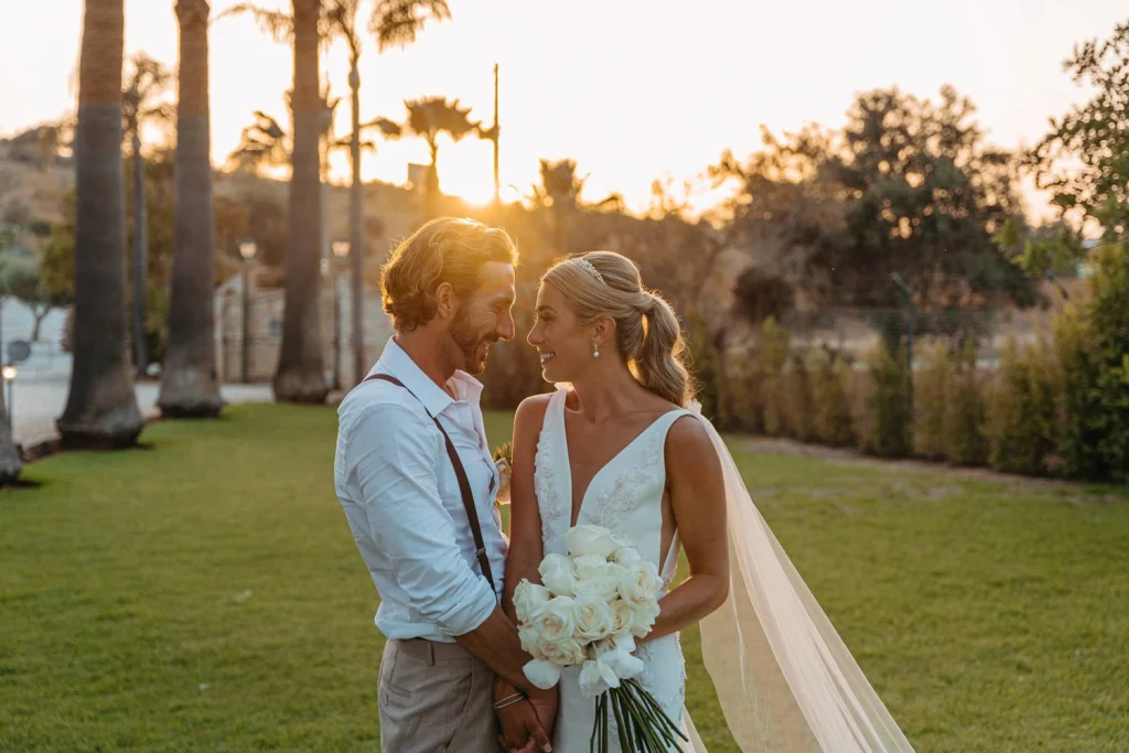 The bride and groom gaze lovingly into each other's eyes during golden hour, holding hands and soaking in the romance of their luxury wedding in Portugal.