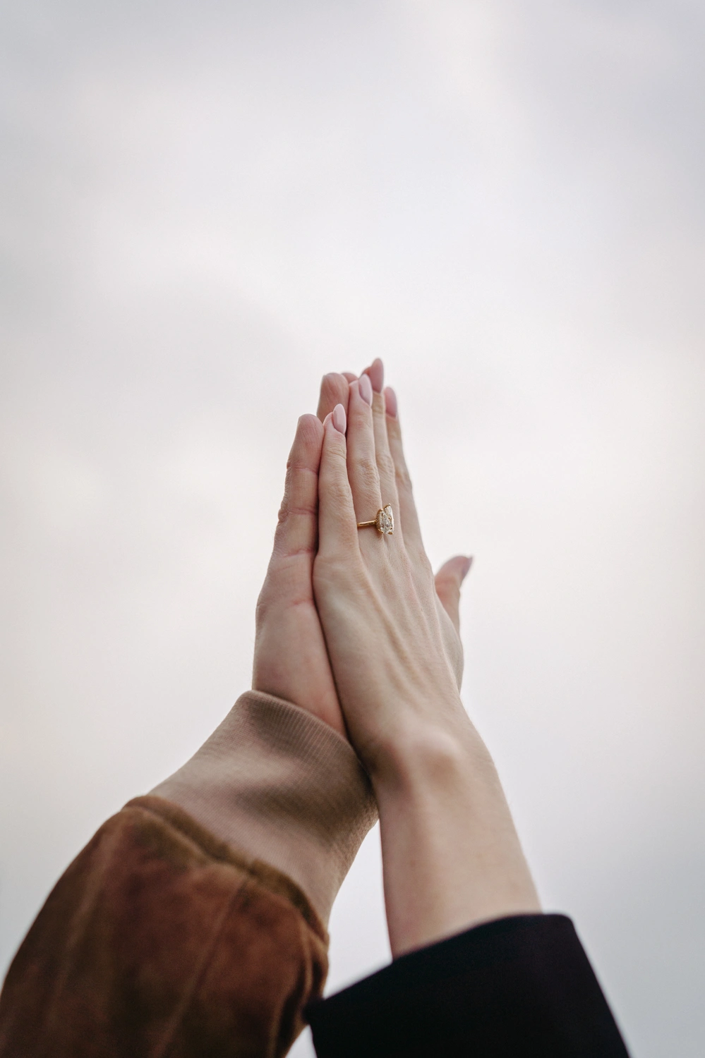 Romantic close-up of a couple’s hands pressed together, highlighting a gold engagement ring with a delicate design in Sintra