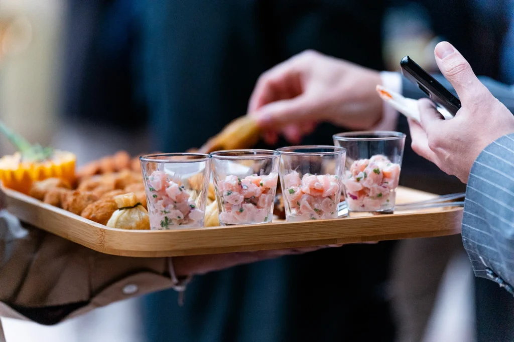 A close-up of gourmet appetizers being served at an upscale event, featuring salmon tartare in glass cups in estufa fria, lisbon