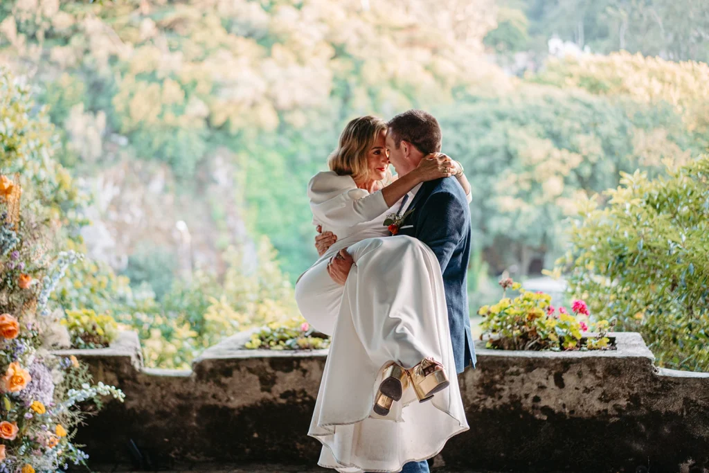 Groom lifts his bride in a romantic pose against a panoramic mountain view