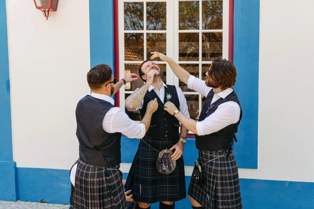 Groomsmen helping the groom get ready, adjusting his boutonnière and fixing his outfit before the wedding ceremony
