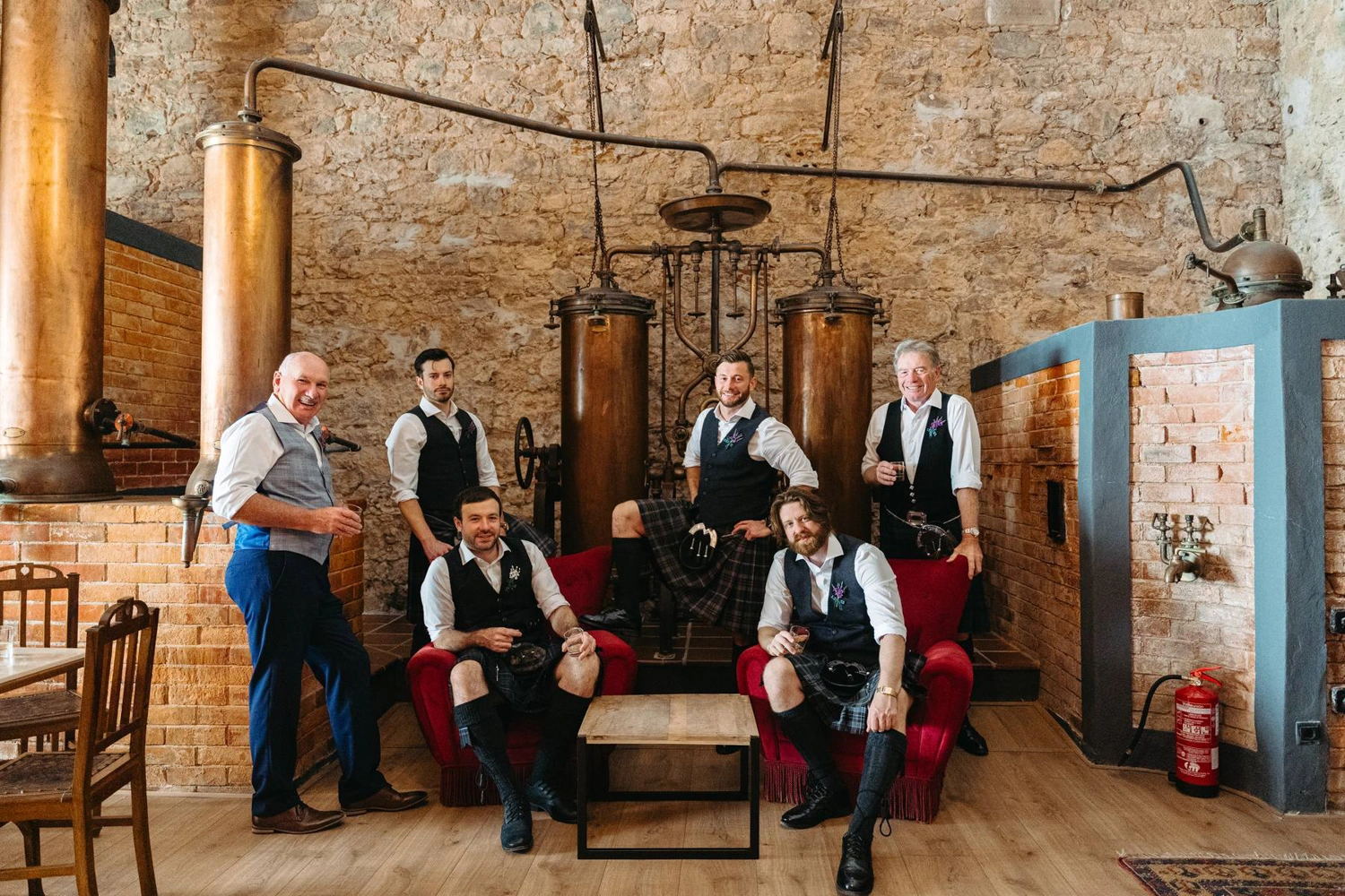 The groom and his wedding party raising a whiskey toast in a rustic bar, celebrating before the ceremony.