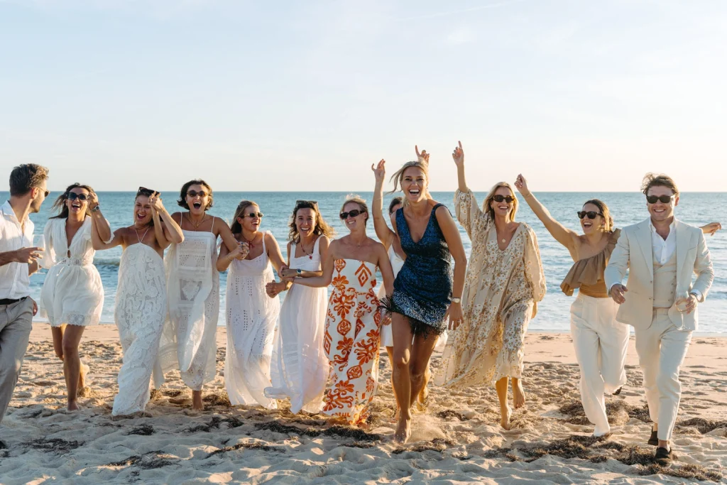 A group of friends running joyfully on the beach, laughing and celebrating a special occasion in Portugal, Algarve.