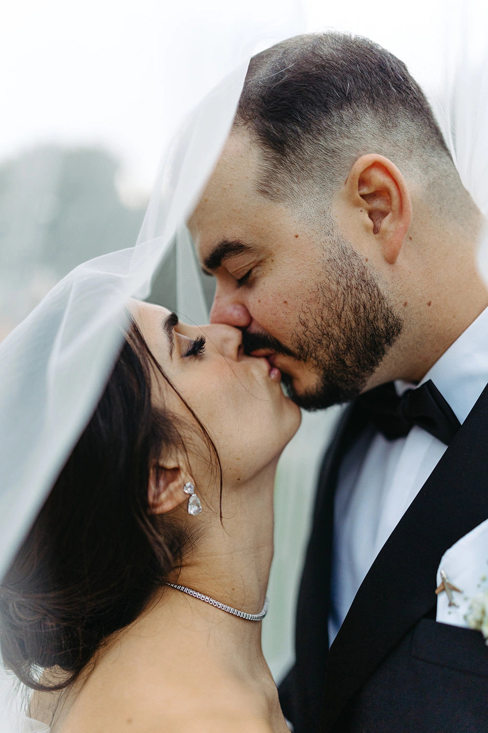 Romantic close-up of bride and groom kissing under her veil.