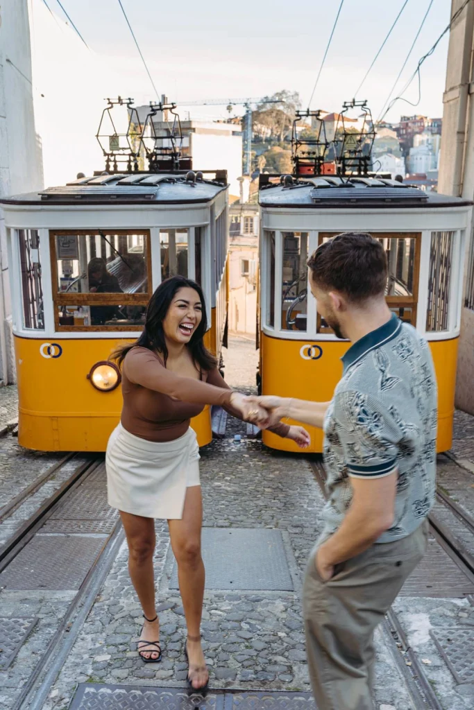 A couple laughs and dances playfully on the tram tracks in Lisbon, adding fun and romance to their love story.