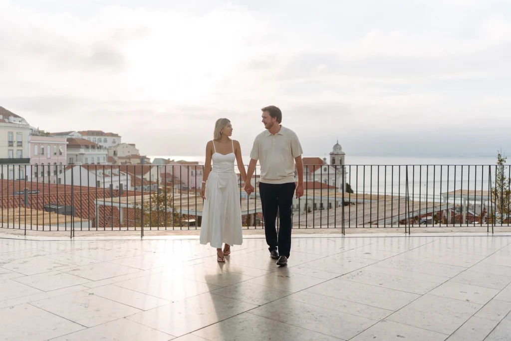 A couple shares a romantic kiss on a Lisbon rooftop, with the historic cityscape creating a breathtaking backdrop.