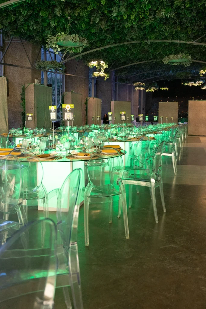 A stunning banquet setup in a luxury event space with glowing green table lighting and clear acrylic chairs.