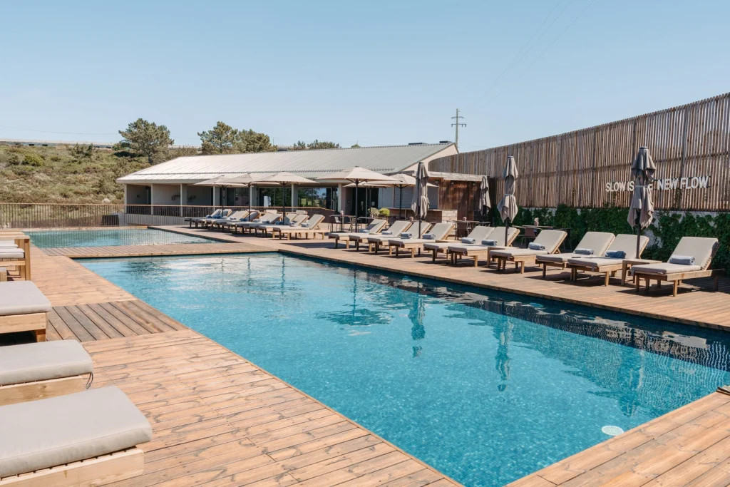A serene poolside retreat at a luxury hotel, surrounded by modern wooden deck seating.