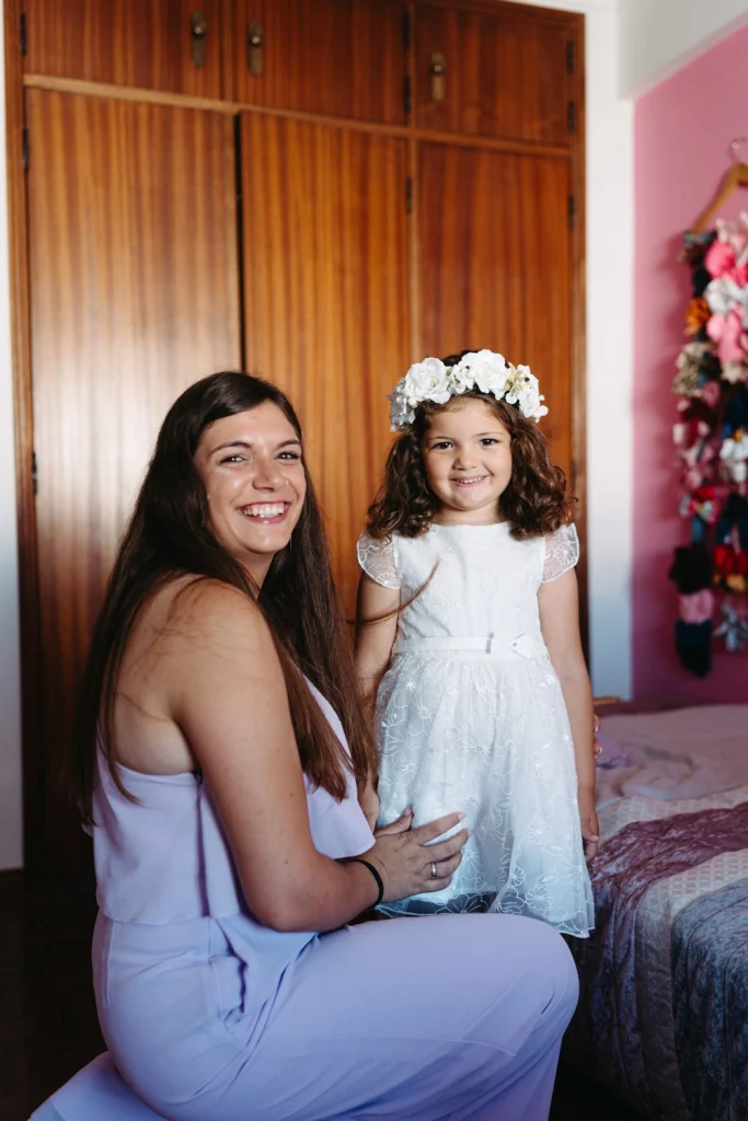 A mother and her daughter smiling while getting ready for a baptism in Portugal.