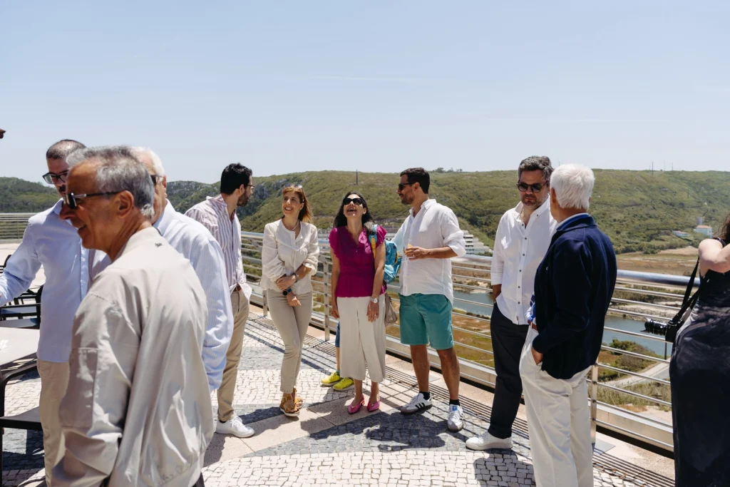 Guests engaging in lively conversations at a stylish rooftop event with panoramic views of the surrounding landscape.