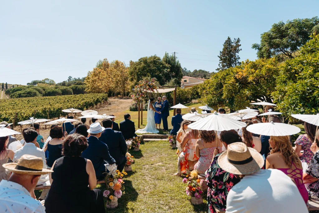 A beautiful outdoor wedding ceremony setup with wooden benches and colorful floral arrangements in quinta de santana