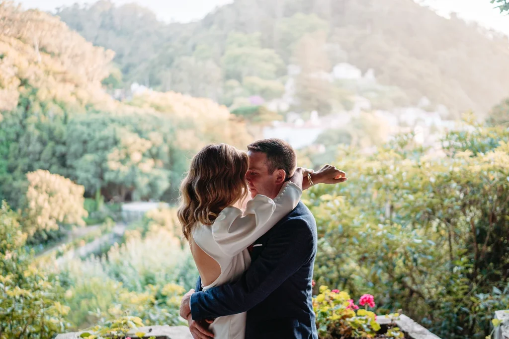 Bride and groom share an intimate embrace with stunning greenery in the background called Camelia Gardens in Sintra