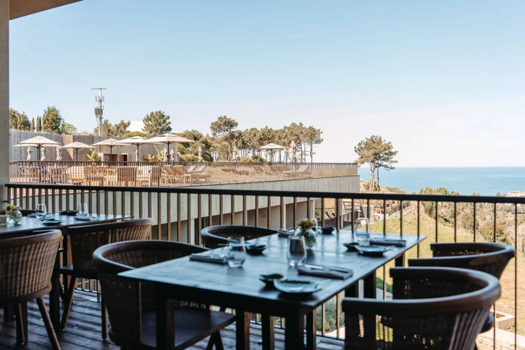 Outdoor restaurant terrace overlooking the ocean, set up for a beautiful dining experience.