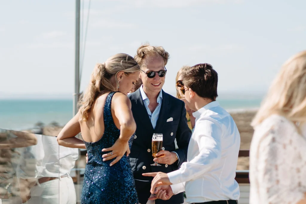 Guests dressed in elegant attire mingling and enjoying conversations at a scenic seaside event in Portugal.