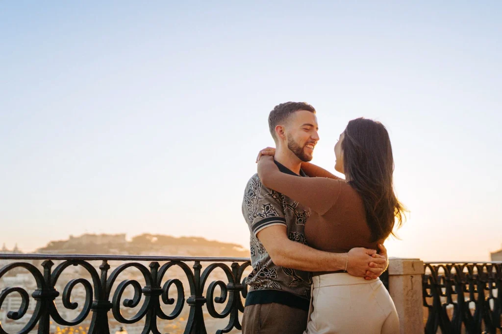 A couple embraces against the golden hues of a Lisbon sunset, enjoying a romantic moment.
