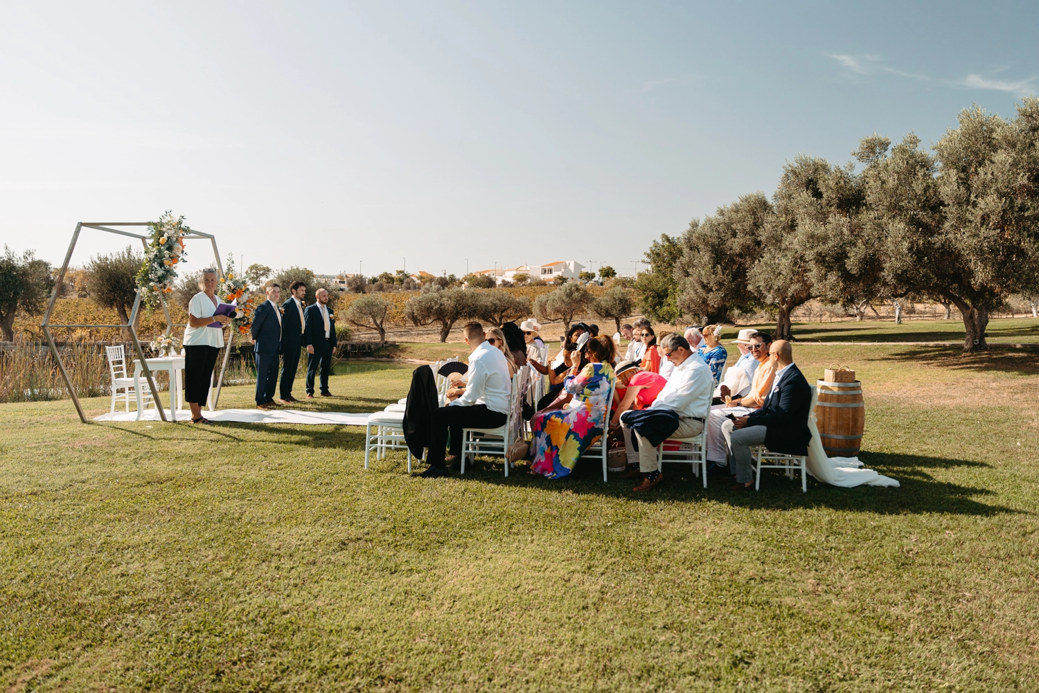 Stunning outdoor wedding ceremony setup with a modern floral arch and white chairs under the Portuguese sun in Algarve