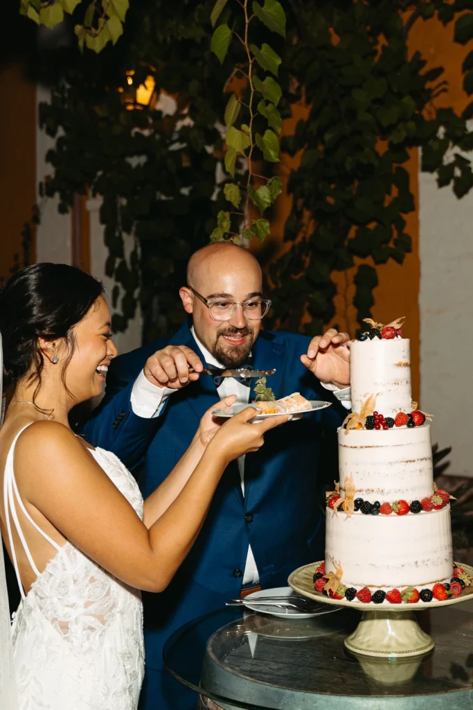 couple sharing a fun moment cutting their wedding cake together at their Portugal reception
