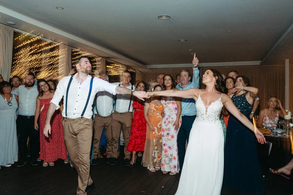 A bride and groom share their first dance surrounded by family and friends.