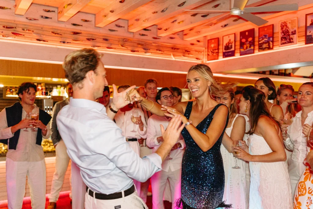A radiant couple dancing together at a stylish wedding reception, surrounded by happy guests.