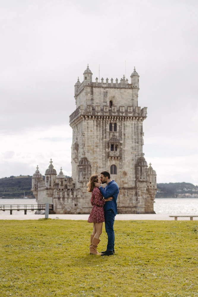 A couple sharing a heartfelt hug on the beach near the Portugal coast, with the ocean waves in the background.