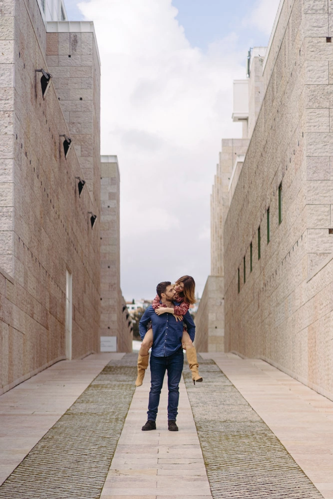 A playful moment of a couple with a piggyback ride in Lisbon’s modern architecture setting.