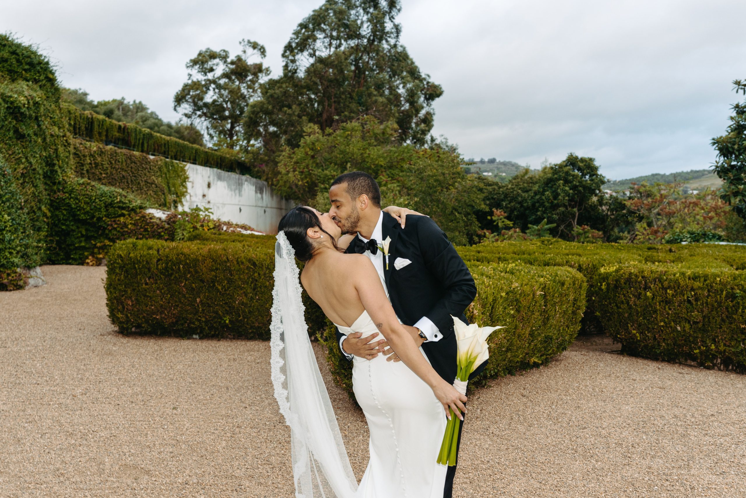 Bride and groom sharing a romantic kiss in the gardens of a luxury wedding venue in Portugal after their ceremony.